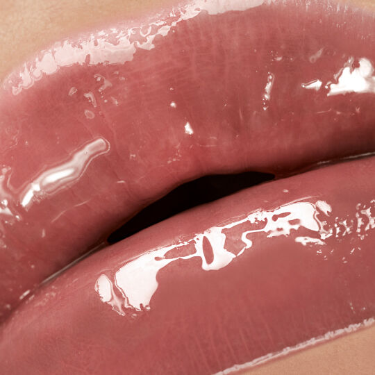Close-up of lips wearing YSL LOVESHINE Candy Glaze in shade 15, showcasing a glossy, rich nude finish.