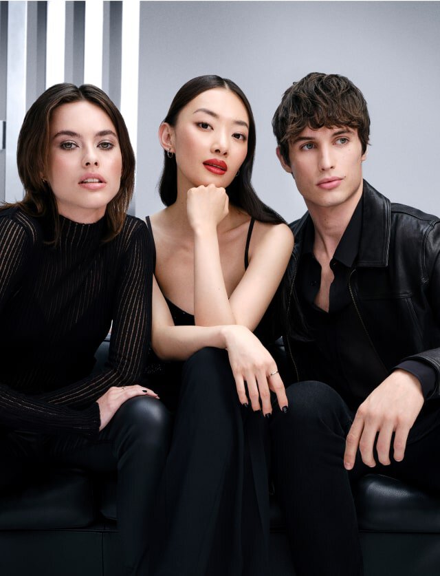 Three models dressed in black seated on a black sofa, representing YSL's loyalty campaign.