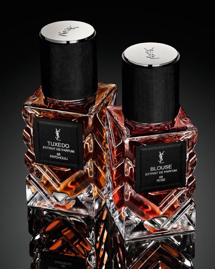 YSL Le Vestiaire des Parfums Tuxedo and Blouse Extrait de Parfum, faceted bottles with black caps, on a reflective black surface.