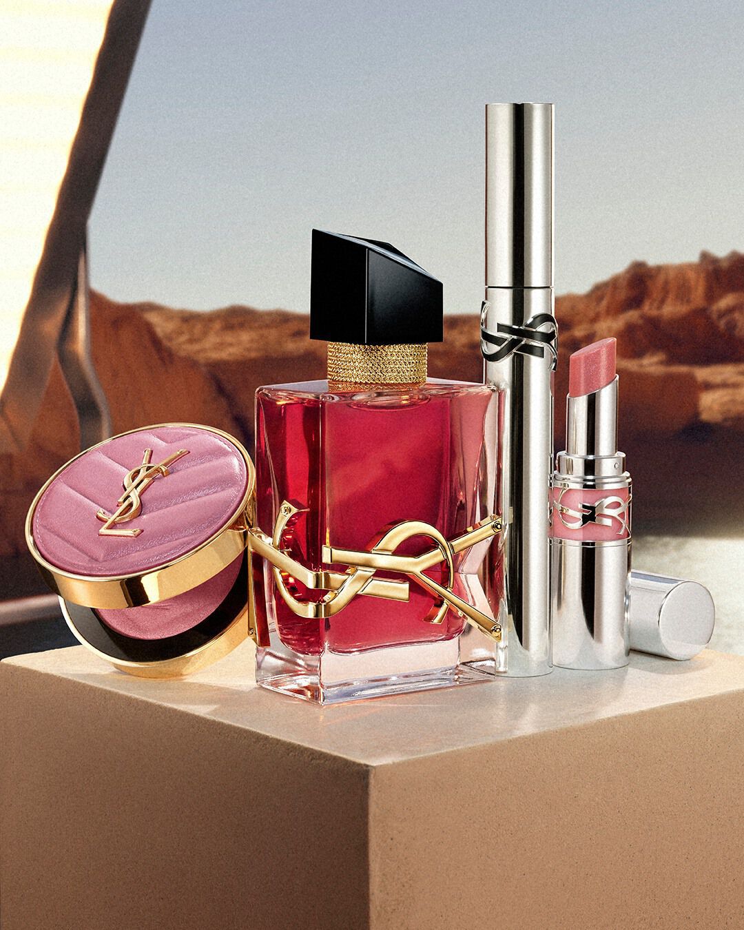 Libre berry crush perfume, Loveshine stardust, Lash Latex mascara, and Make Me Blush Powder on a beige pedestal.