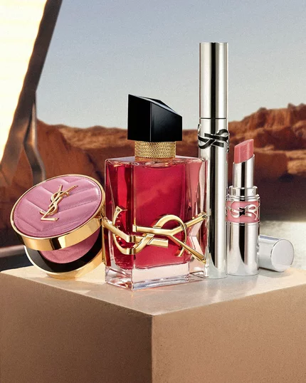 Libre berry crush perfume, Loveshine stardust, Lash Latex mascara, and Make Me Blush Powder on a beige pedestal.