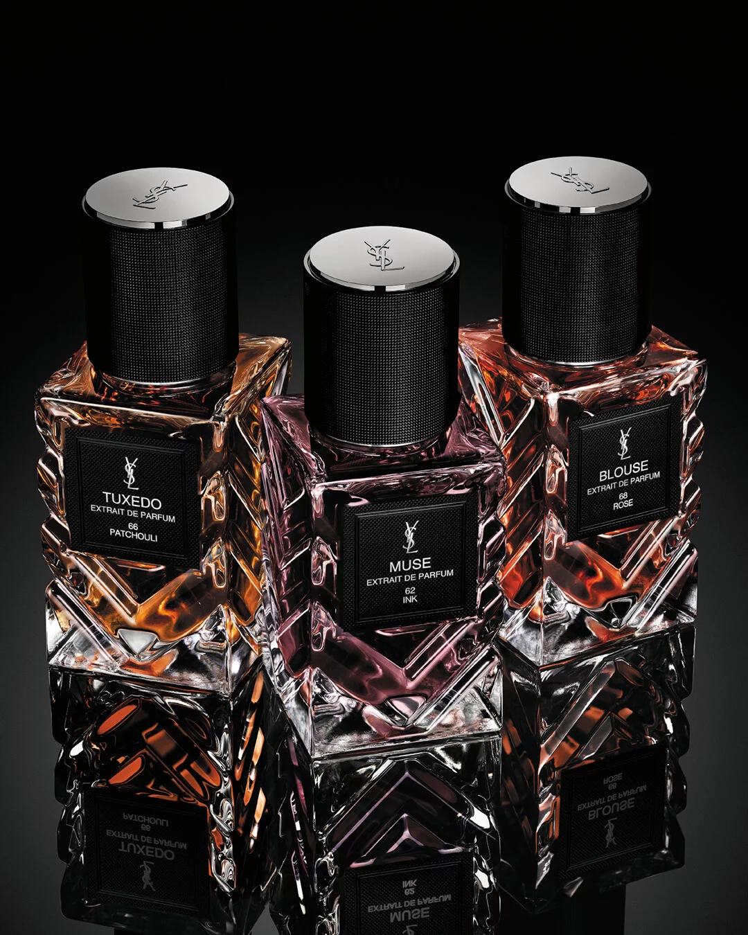 YSL Le Vestiaire des Parfums Tuxedo and Blouse Extrait de Parfum, faceted bottles with black caps, on a reflective black surface.