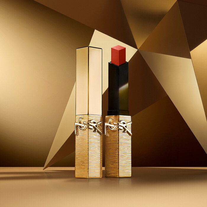 Rouge Pur Couture The Slim Matte Lipstick Collector in shade 1936 in a textured gold case, displayed on a geometric gold-toned background.