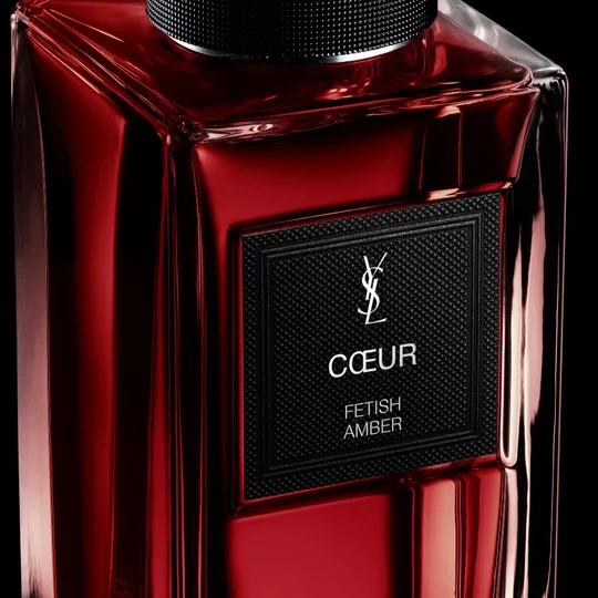 Close-up of the COEUR fragrance label on the ruby-red glass bottle, part of Le Vestiaire des Parfums