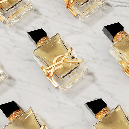 Flat lay of YSL Libre Eau de Parfum bottles on a white marble background.