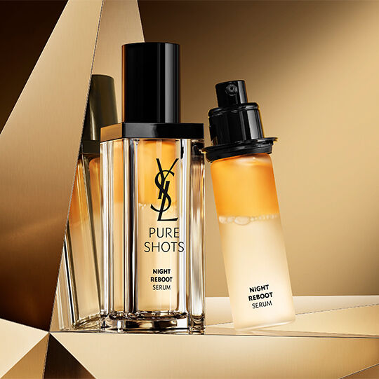 Pure Shots Night Reboot Serum and refill displayed on a reflective golden background.