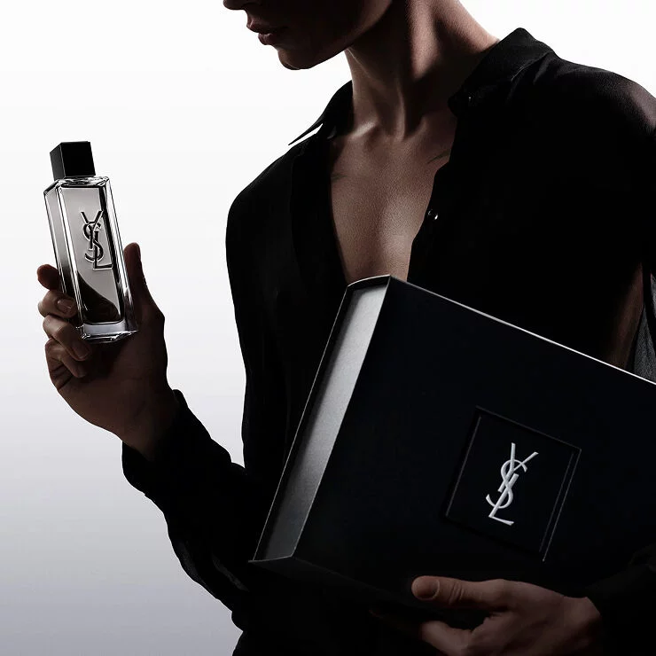 Model holding the MYSLF Eau de Toilette Intense bottle alongside a black YSL Beauty gift box.