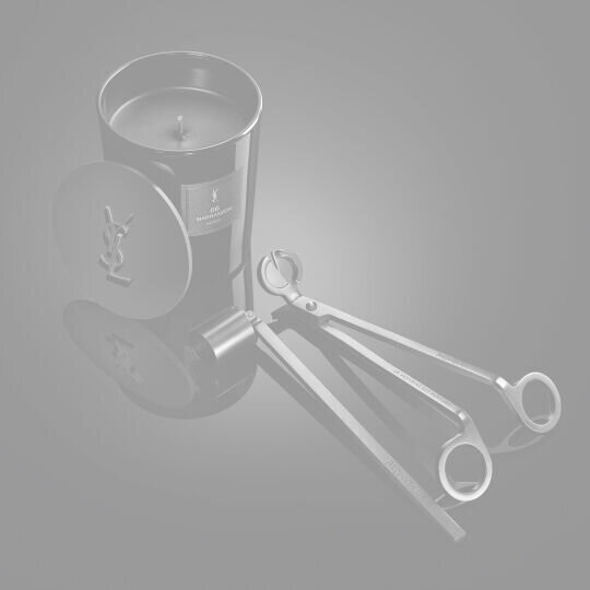 YSL LVDP Marrakech Candle, lid with YSL logo, snuffer, and wick trimmer on a sleek, reflective black surface.