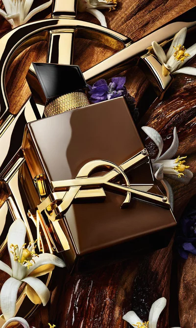 Libre Santal Couture bottle on raw sandalwood bark with a golden YSL Cassandre in the background.