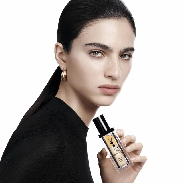 YSL Beauty model with a sleek ponytail and gold hoop earrings, holding the Pure Shots Night Reboot Serum.