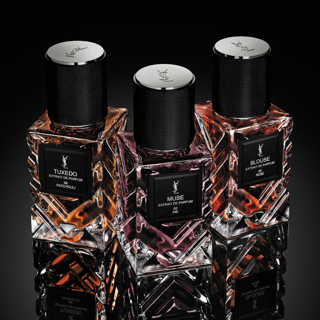 YSL Le Vestiaire des Parfums Tuxedo and Blouse Extrait de Parfum, faceted bottles with black caps, on a reflective black surface.