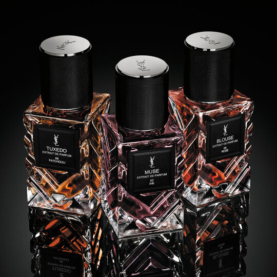 YSL Le Vestiaire des Parfums Tuxedo and Blouse Extrait de Parfum, faceted bottles with black caps, on a reflective black surface.