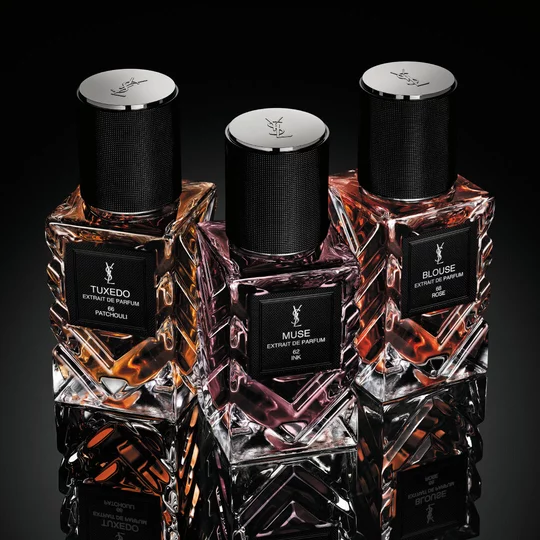 YSL Le Vestiaire des Parfums Tuxedo and Blouse Extrait de Parfum, faceted bottles with black caps, on a reflective black surface.
