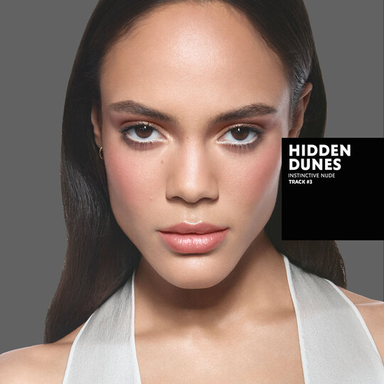 Kalixte, medium skin tone, with an instinctive nude eye look and hidden dunes glossy lips, wearing a white top.