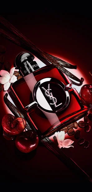 Black Opium Over Red bottle in deep red lacquer surrounded by fresh red cherries and roasted coffee beans.