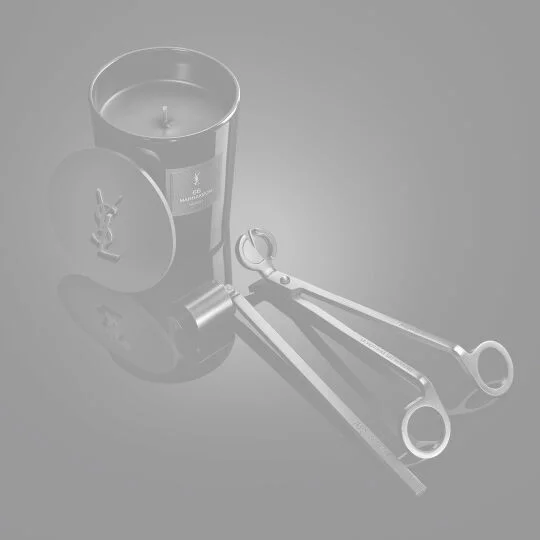 YSL LVDP Marrakech Candle, lid with YSL logo, snuffer, and wick trimmer on a sleek, reflective black surface.