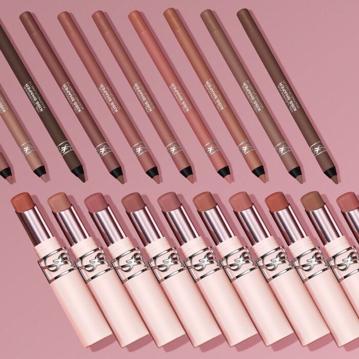 YSL LOVENUDE Kiss Shaper pencils and Lip Blusher lipsticks in various shades, arranged on a pink background.