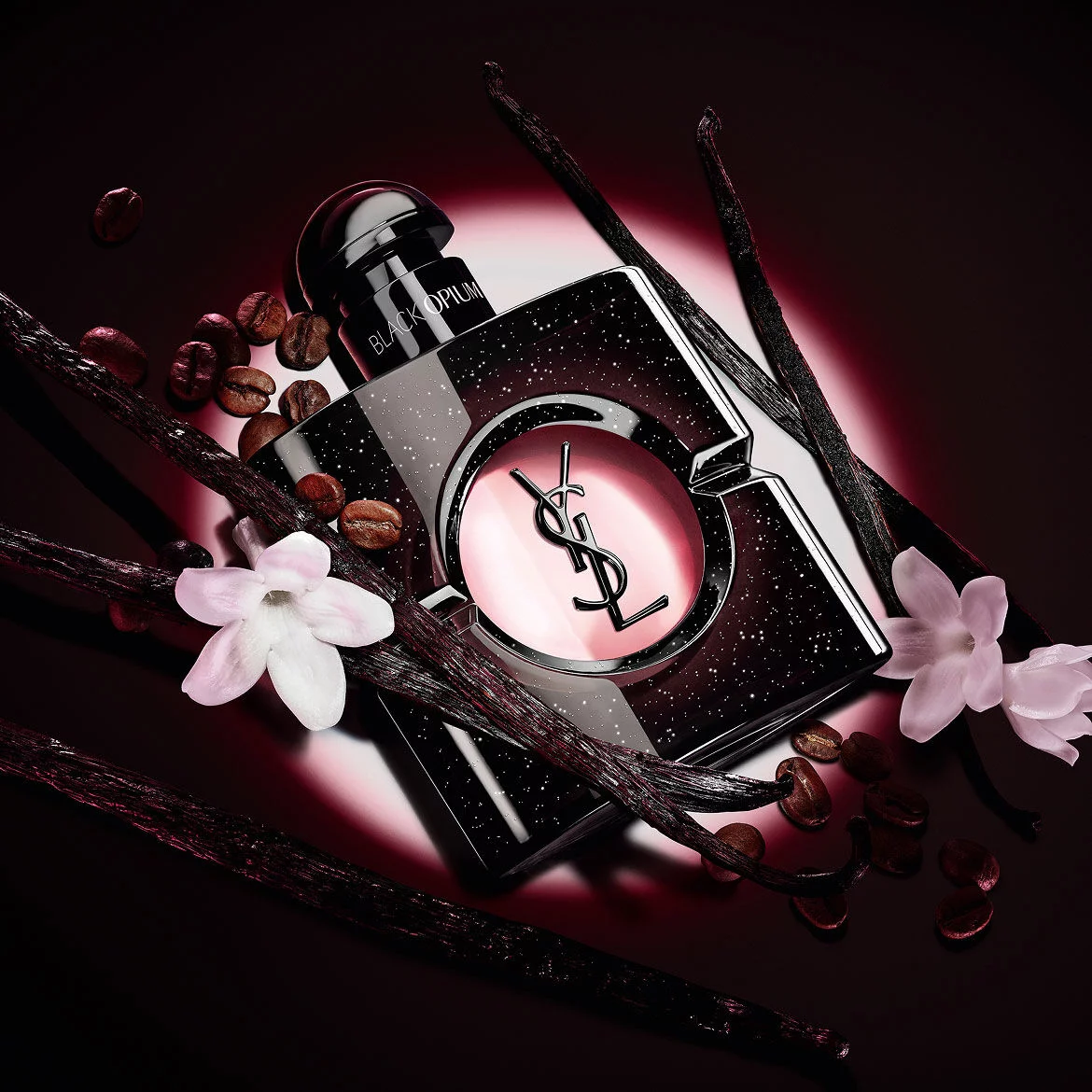 Black Opium Eau de Parfum bottle with white jasmine flowers, vanilla pods, and roasted coffee beans.