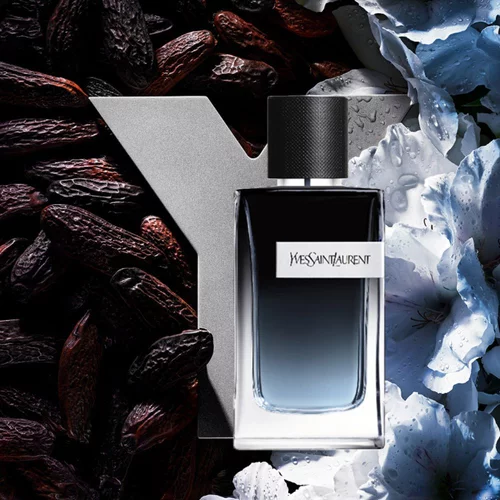 YSL Y Eau de Parfum bottle, with a blue gradient, silver Y logo, surrounded by tonka beans and delicate white, dewy flowers.