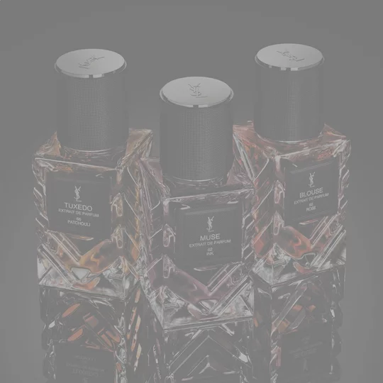 YSL Le Vestiaire des Parfums Tuxedo and Blouse Extrait de Parfum, faceted bottles with black caps, on a reflective black surface.