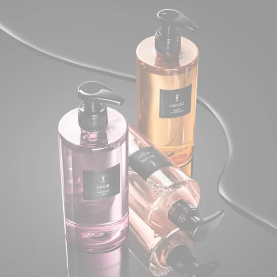 YSL LVDP Hand & Body Wash range: Muse, Tuxedo, and Blouse bottles on a sleek, reflective black surface.