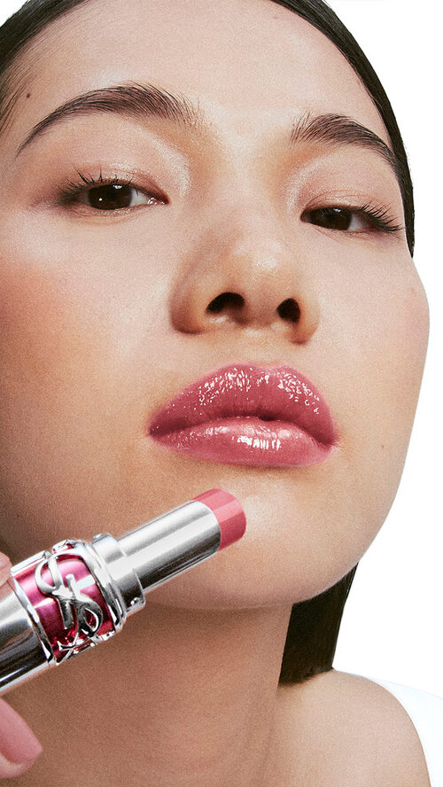 Model Jiangyue, fair skin tone, applying YSL Loveshine Candy Glaze in shade 44 Nude Lavalliere to her glossy lips.