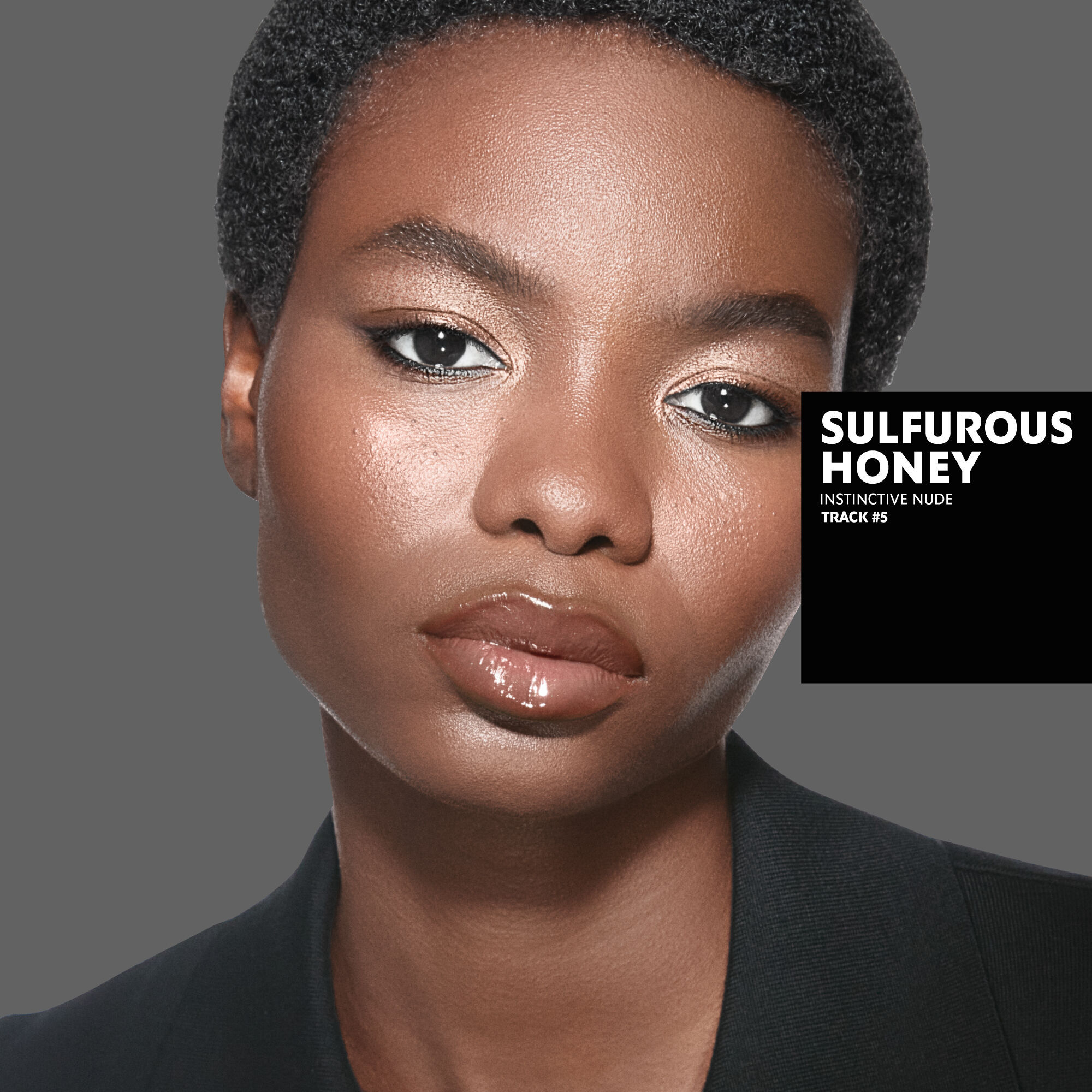 Marie, dark skin tone, with an instinctive nude eye look and sulfurous honey glossy lips, wearing a black blazer.
