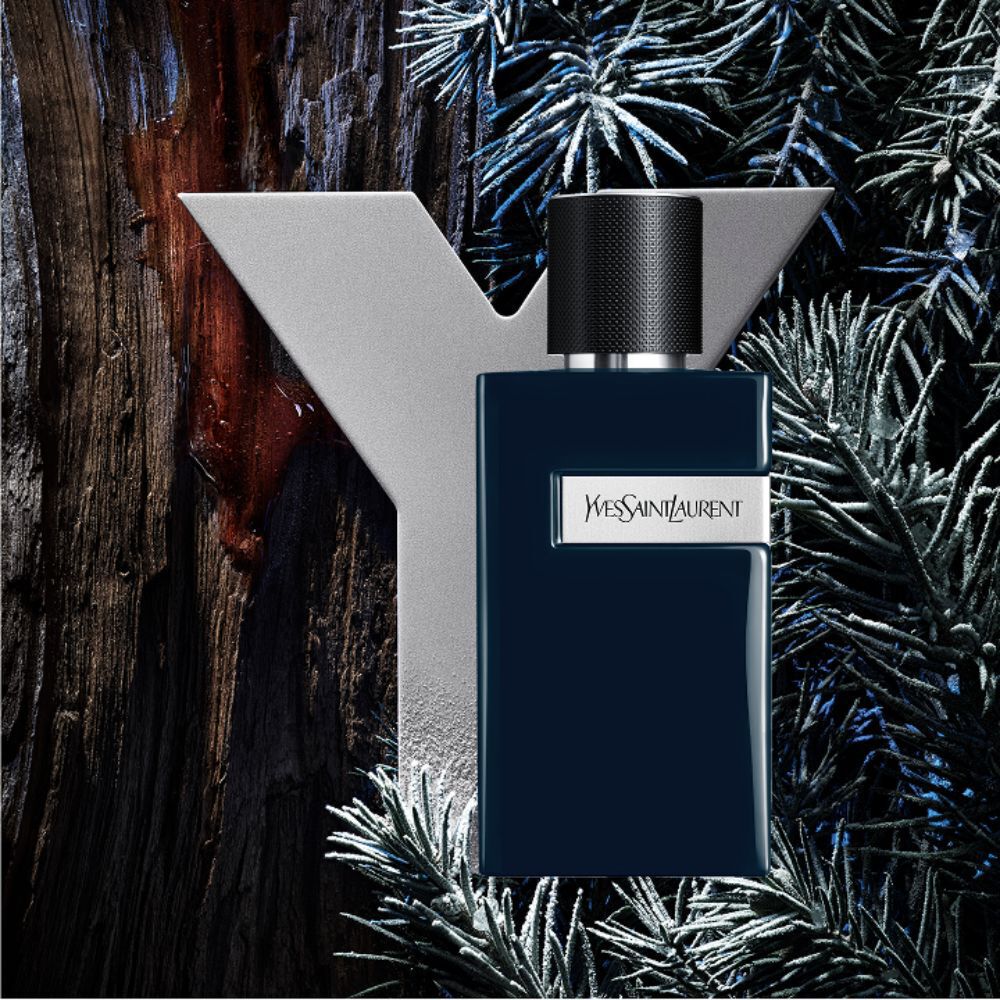 YSL Y Le Parfum bottle, dark blue with silver Y logo, set against a  rustic wooden background and frosted pine branches.