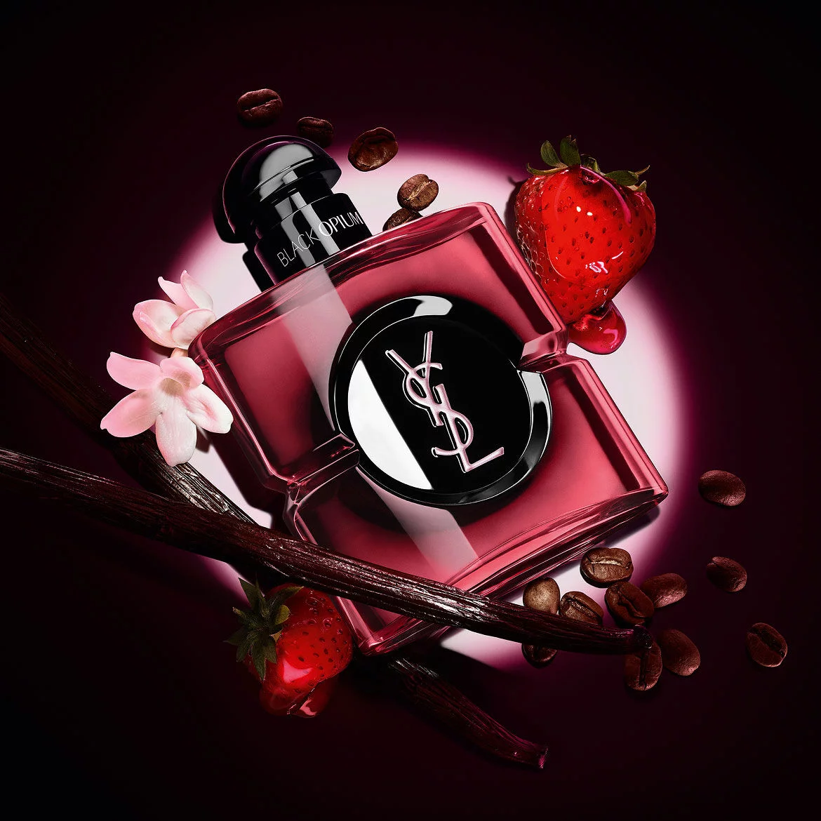 Black Opium Eau de Parfum Pink Glaze bottle surrounded by fresh strawberries, vanilla pods, coffee beans, and jasmine.