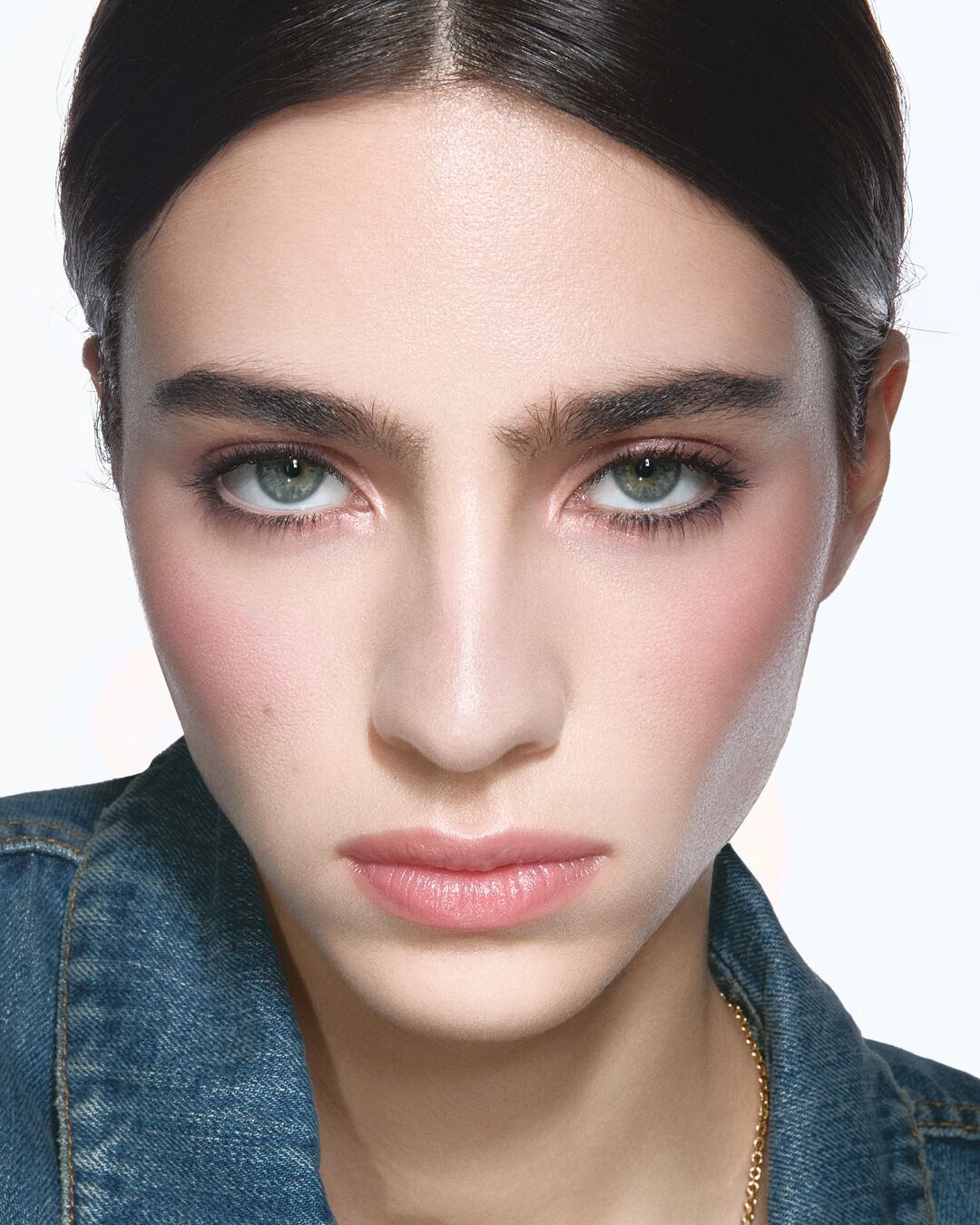 Loli, light skin tone, with an instinctive nude eye look and subtle obsession dunes glossy lips, wearing a denim jacket.