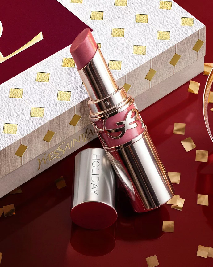 Engraved YSL Loveshine displayed with a luxury holiday gift box in the background on a festive glossy burgundy setting.