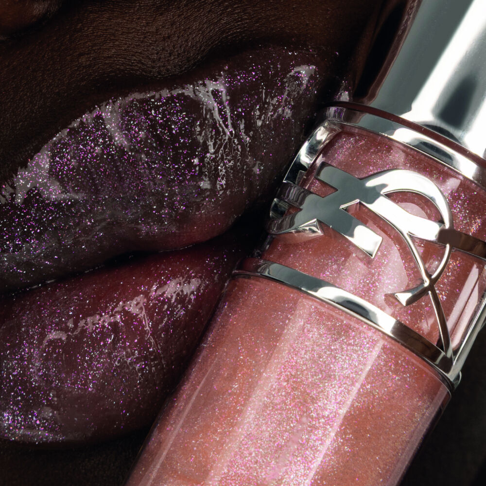 Nyaluak, YSL Beauty model, with YSL LOVESHINE Plumping Lip Oil Gloss shade 10 near her deep-toned, shimmering lips.