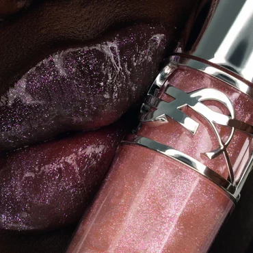 Nyaluak, YSL Beauty model, with YSL LOVESHINE Plumping Lip Oil Gloss shade 10 near her deep-toned, shimmering lips.