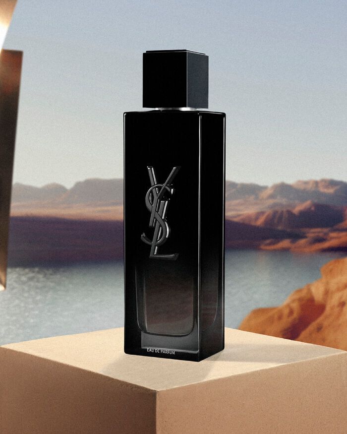 YSL MYSLF EDP 100ml perfume bottle, sleek black design, on a beige pedestal with a studio light in a desert landscape.