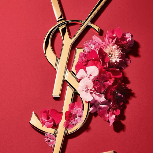 Gold YSL Cassandre logo adorned with vibrant pink spring flowers, set against a pink background.