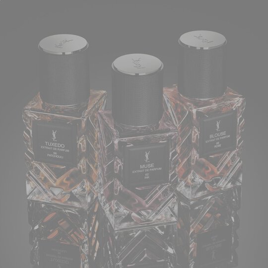 YSL Le Vestiaire des Parfums Tuxedo and Blouse Extrait de Parfum, faceted bottles with black caps, on a reflective black surface.