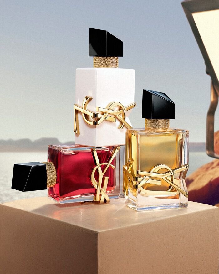 YSL LIBRE EDP, LIBRE EAU NUE, and LIBRE BERRY CRUSH perfumes on a pedestal with studio light in a desert landscape.