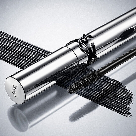 YSL Lash Clash mascara on a reflective surface, showcasing the bold black texture and couture packaging.