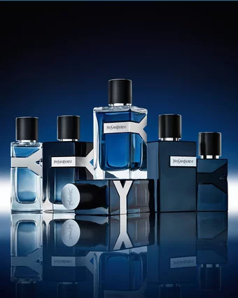 A collection of YSL Y fragrances, showcasing various blue bottles with iconic Y logos, arranged elegantly on a reflective surface.