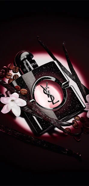 Black Opium Eau de Parfum bottle with white jasmine flowers, vanilla pods, and roasted coffee beans.