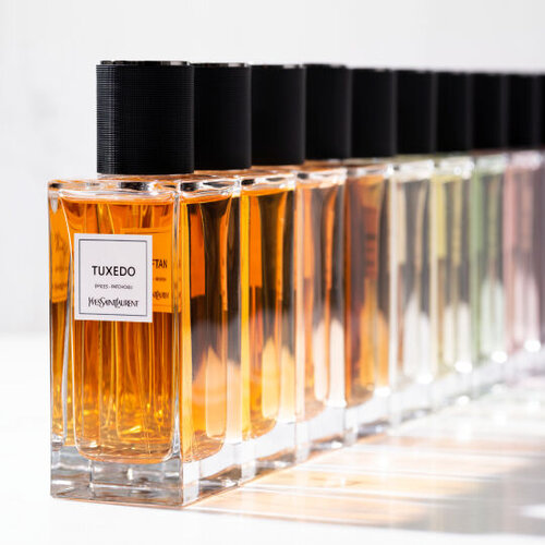 YSL Collection Essentielle perfumes Le Vestiaire des Parfums arranged on a reflective dark surface.