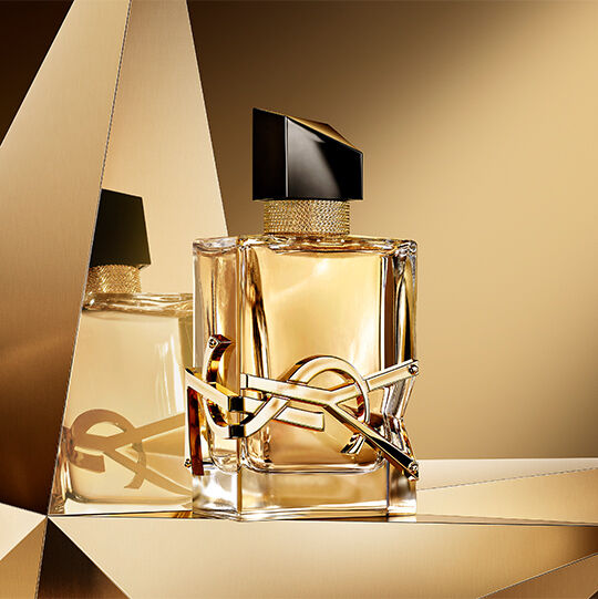 Libre eau de parfum bottle displayed on a reflective golden background.