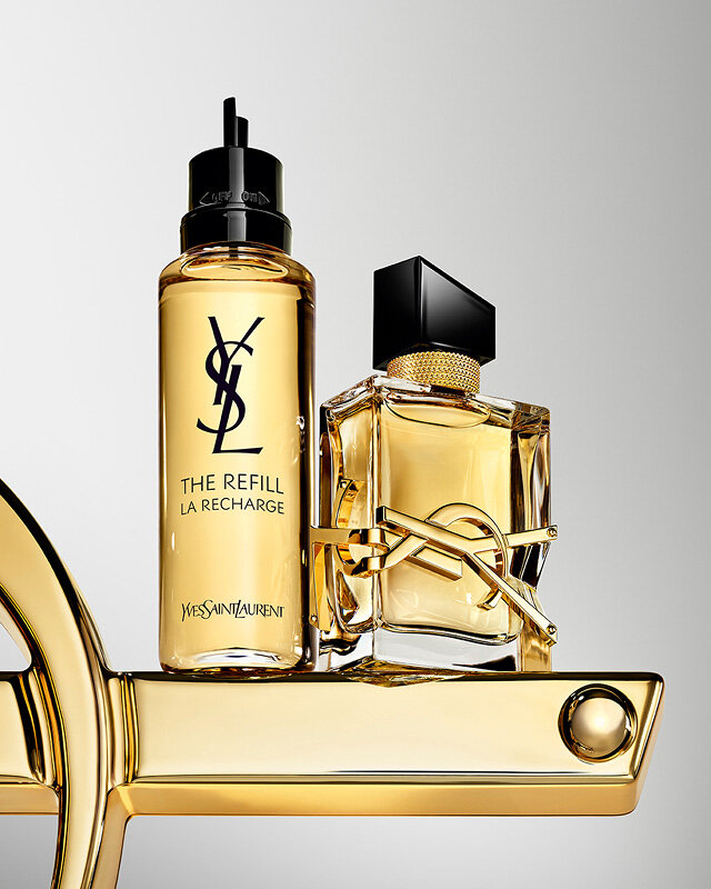 Libre Eau de Parfum bottle and refill bottle displayed with oversized gold YSL logo.
