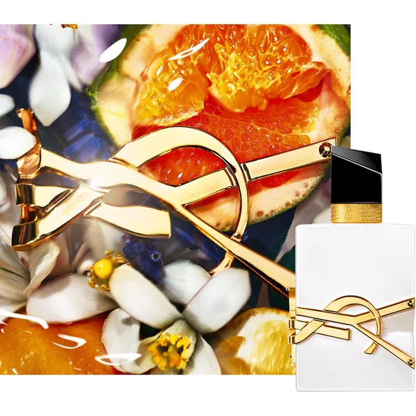Libre L’EAU NUE alcohol-free bottle styled with white flowers and soft golden lighting.