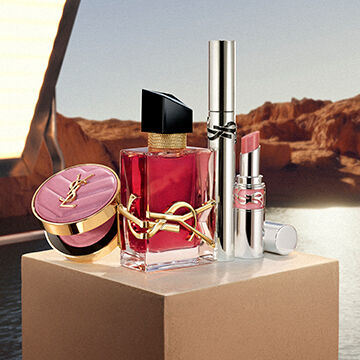 Libre berry crush perfume, Loveshine stardust, Lash Latex mascara, and Make Me Blush Powder on a beige pedestal.