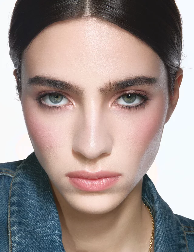 Loli, light skin tone, with an instinctive nude eye look and subtle obsession dunes glossy lips, wearing a denim jacket.