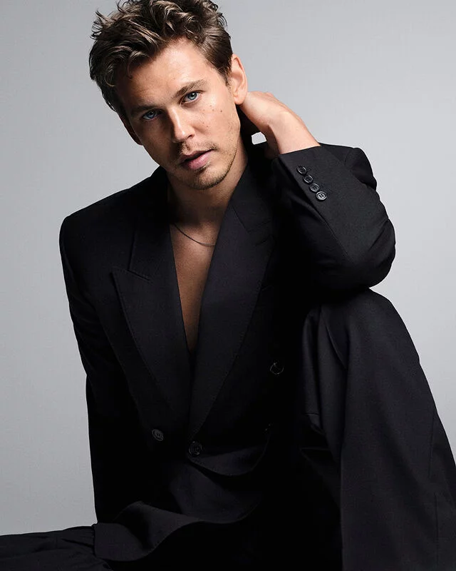 Austin Butler posing in a black suit against a grey background for the MYSLF Eau de Toilette Intense campaign.