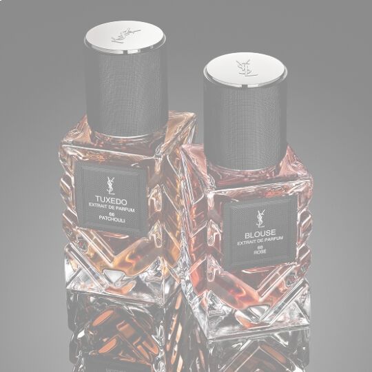 YSL Le Vestiaire des Parfums Tuxedo and Blouse Extrait de Parfum, faceted bottles with black caps, on a reflective black surface.