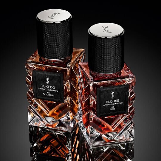YSL Le Vestiaire des Parfums Tuxedo and Blouse Extrait de Parfum, faceted bottles with black caps, on a reflective black surface.