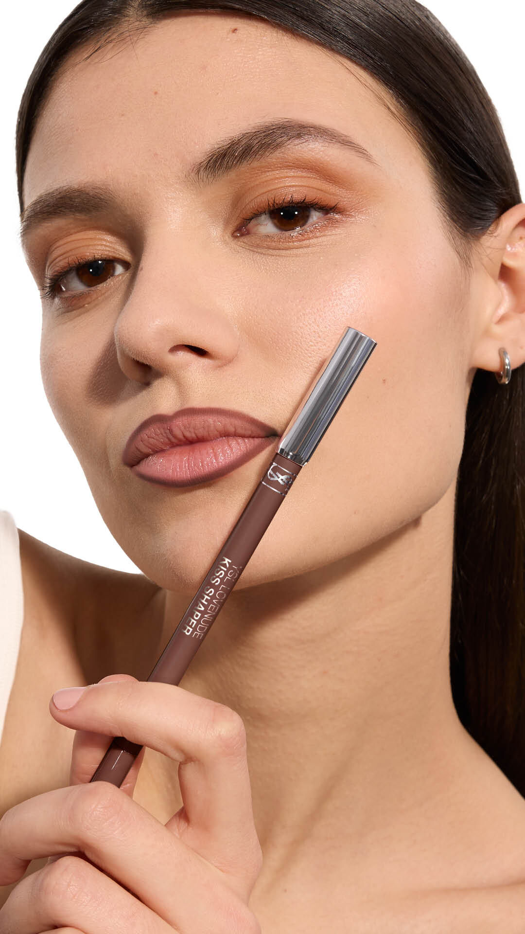 Adrienne holding YSL LOVENUDE Kiss Shaper 26 in Shade 107, full- face portrait on white background.
